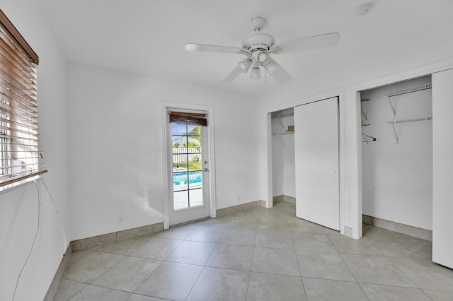 unfurnished bedroom featuring multiple closets, light tile patterned floors, and ceiling fan