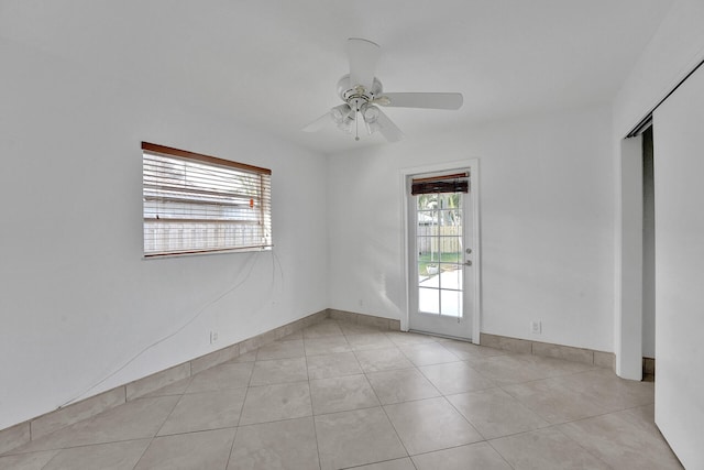 tiled empty room featuring a wealth of natural light and ceiling fan