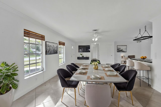 dining space with crown molding, a healthy amount of sunlight, ceiling fan, and light tile patterned flooring