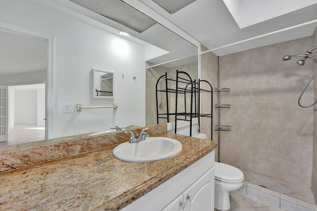 bathroom with toilet, vanity, tile patterned flooring, and a tile shower