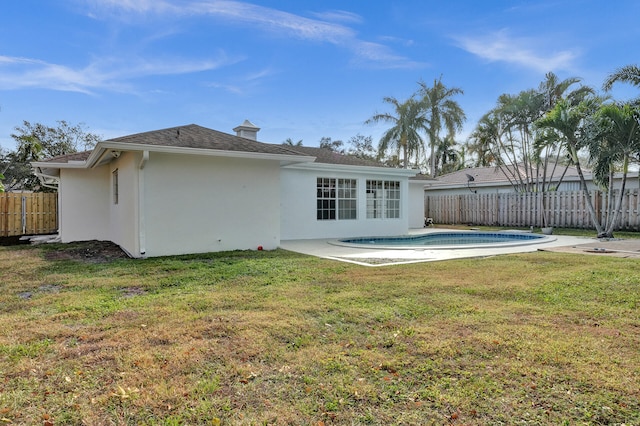 rear view of house featuring a patio, a fenced in pool, and a yard