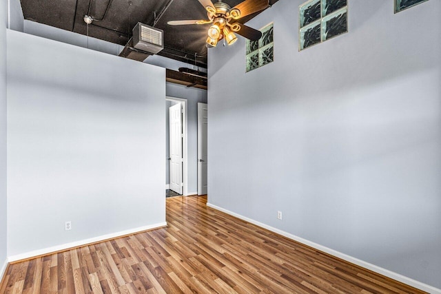 unfurnished room featuring a high ceiling, wood-type flooring, and ceiling fan