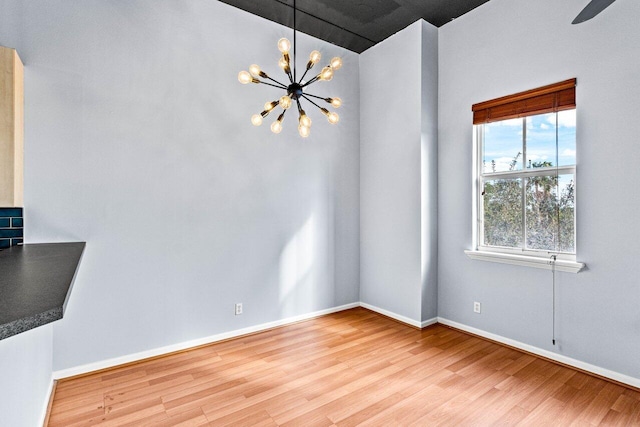 interior space featuring ceiling fan with notable chandelier and light hardwood / wood-style flooring