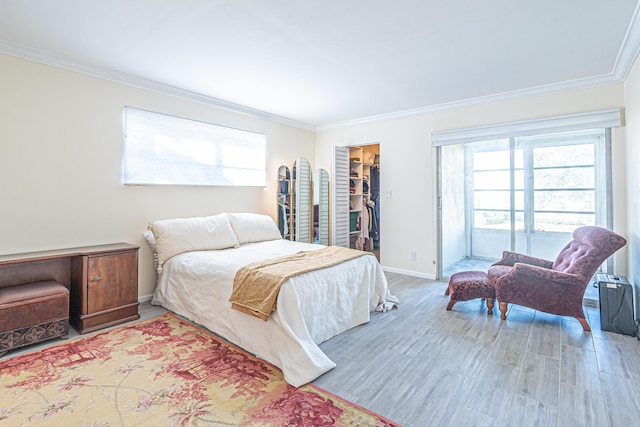 bedroom featuring wood-type flooring, a spacious closet, a closet, and crown molding