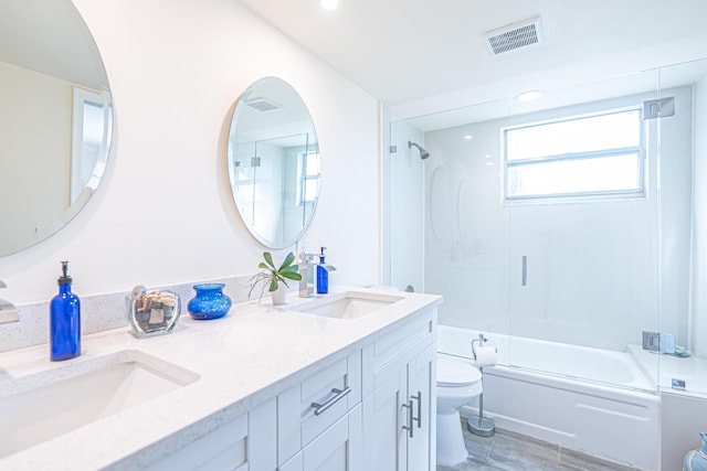 full bathroom with vanity, bath / shower combo with glass door, and toilet