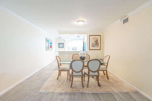 dining space with crown molding and light wood-type flooring