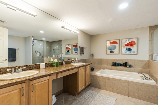 bathroom featuring plus walk in shower, vanity, a textured ceiling, and tile patterned flooring