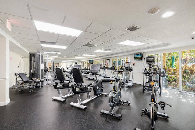 gym with a drop ceiling and a healthy amount of sunlight