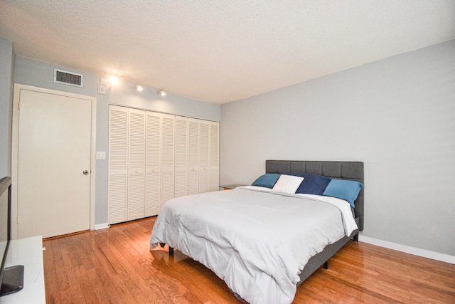 bedroom featuring a textured ceiling, a closet, and light wood-type flooring