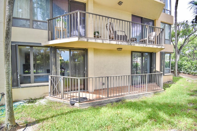 rear view of house with a lawn and a balcony