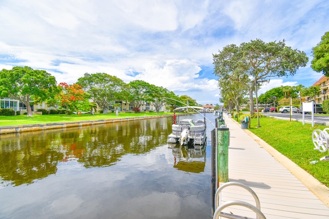 view of dock with a yard and a water view