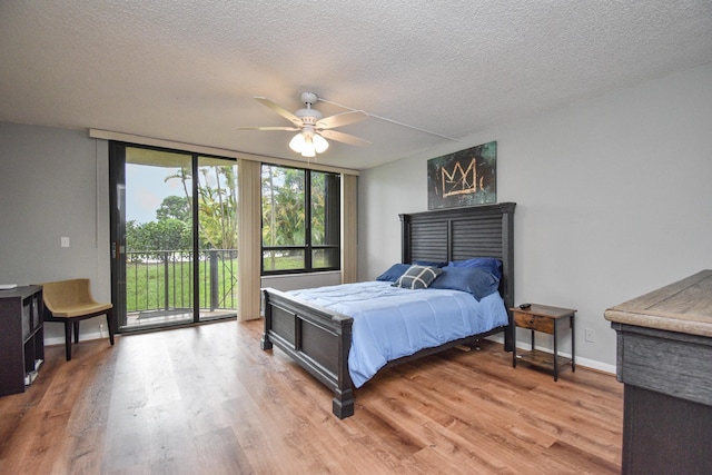 bedroom with a textured ceiling, access to exterior, floor to ceiling windows, hardwood / wood-style floors, and ceiling fan