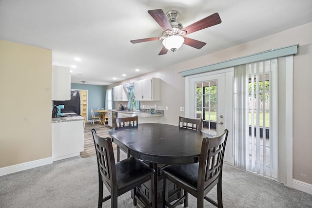 carpeted dining area with ceiling fan