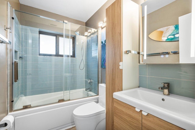 full bathroom with decorative backsplash, vanity, combined bath / shower with glass door, and toilet