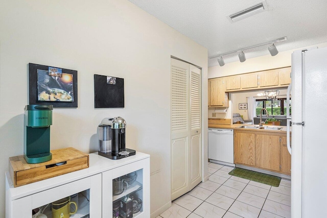 kitchen featuring sink, track lighting, a textured ceiling, an inviting chandelier, and white appliances