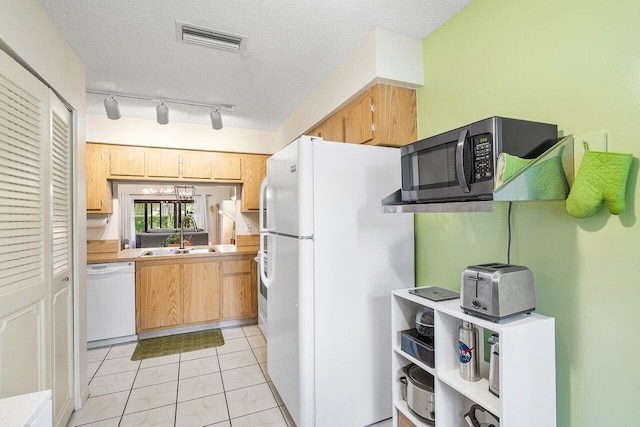 kitchen featuring a textured ceiling, sink, white appliances, and light tile patterned floors