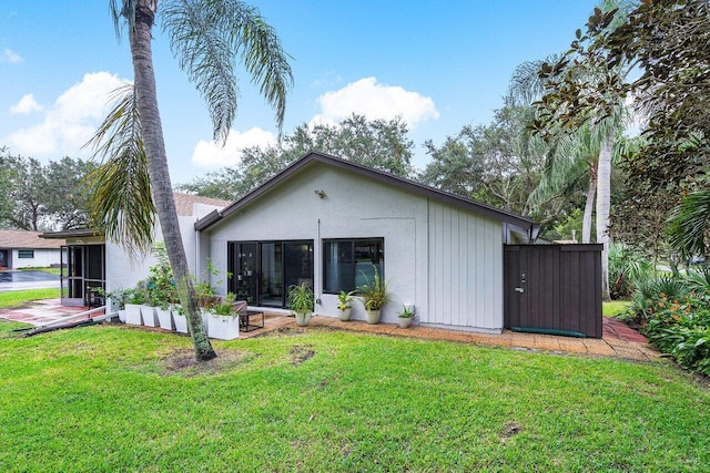 rear view of house featuring a lawn, a patio, and a sunroom