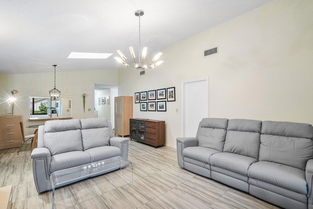 living room featuring lofted ceiling with skylight, an inviting chandelier, and a textured ceiling