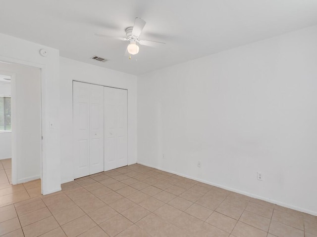 unfurnished bedroom featuring a closet, light tile patterned floors, ceiling fan, and baseboards