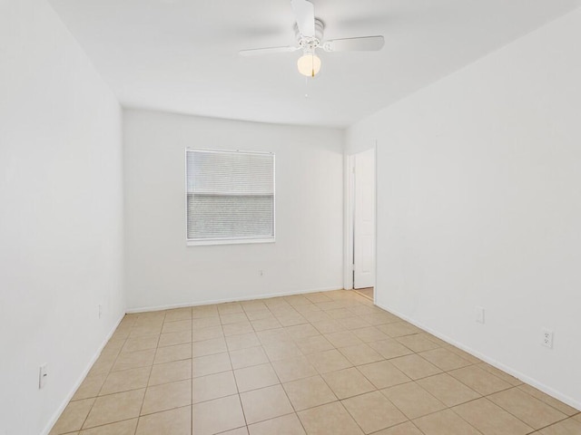 empty room featuring ceiling fan, light tile patterned floors, and baseboards
