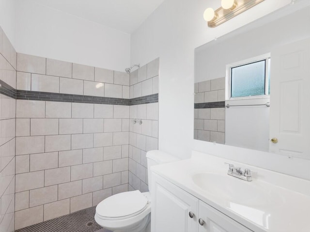 bathroom with toilet, vanity, tile patterned floors, and tiled shower