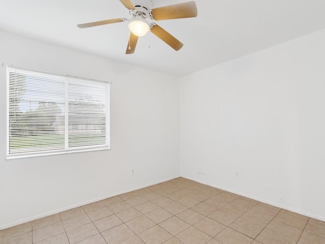 spare room featuring a ceiling fan, baseboards, and light tile patterned floors