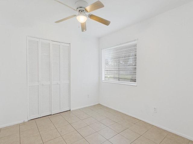 unfurnished bedroom with light tile patterned flooring, ceiling fan, and a closet