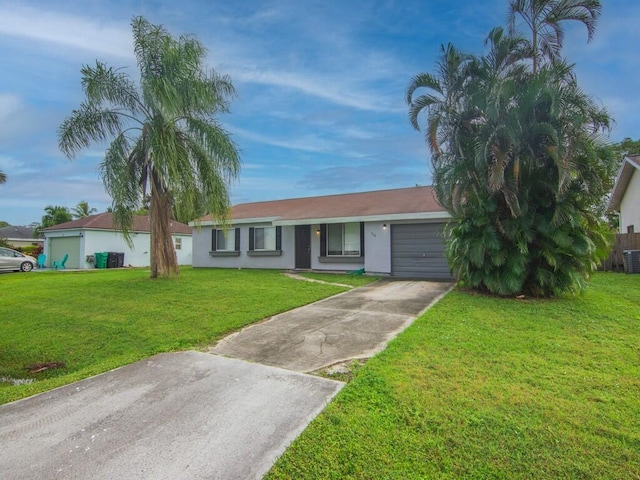 ranch-style house featuring a garage, a front yard, concrete driveway, stucco siding, and central AC unit