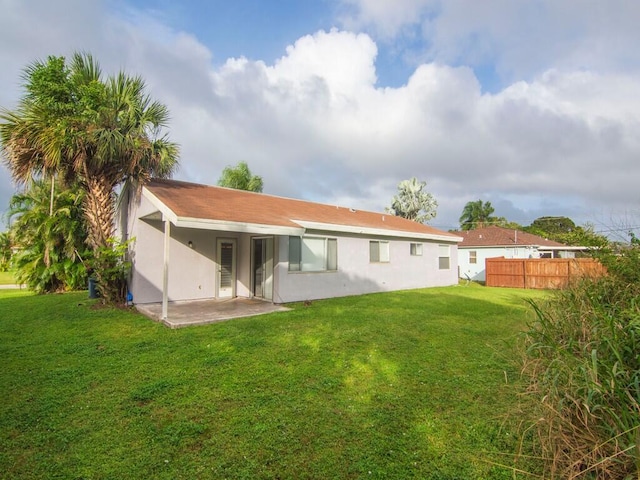 rear view of property featuring a patio and a yard