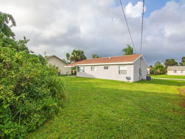 back of house featuring central air condition unit and a lawn