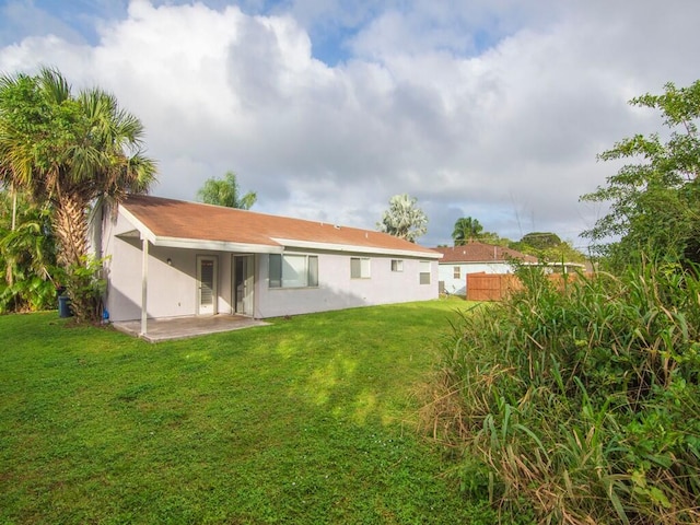 back of house with a patio area and a lawn