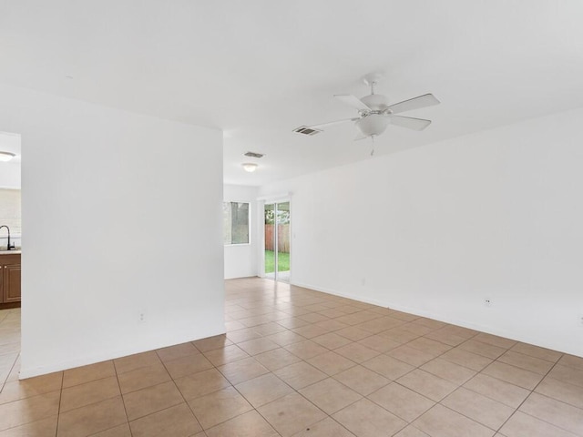 empty room with sink, light tile patterned floors, and ceiling fan