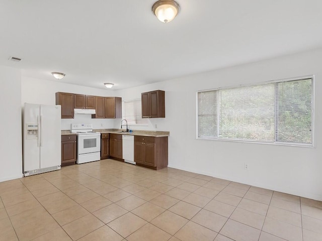 kitchen featuring light tile patterned floors, white appliances, and sink