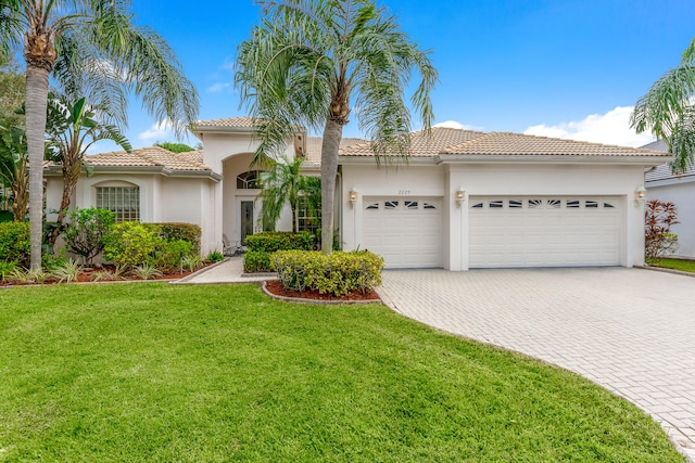 mediterranean / spanish home featuring a garage and a front yard