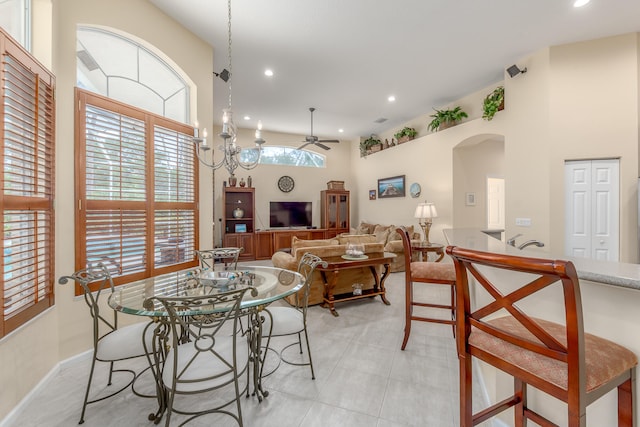 dining area featuring a towering ceiling and ceiling fan with notable chandelier