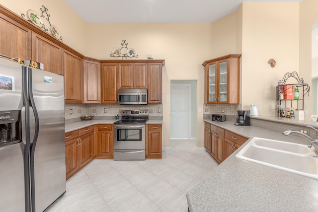 kitchen featuring tasteful backsplash, sink, light tile patterned floors, and stainless steel appliances