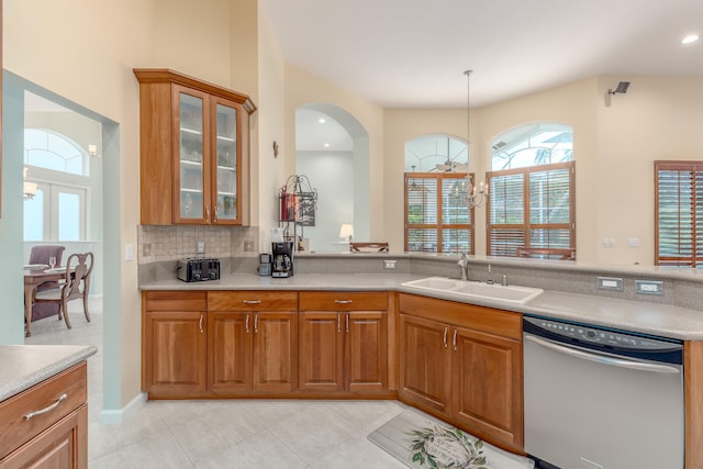 kitchen with light tile patterned flooring, sink, stainless steel dishwasher, hanging light fixtures, and decorative backsplash