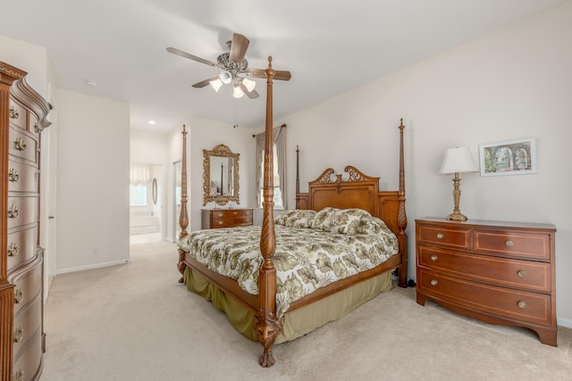 bedroom featuring ceiling fan, ensuite bath, and light colored carpet