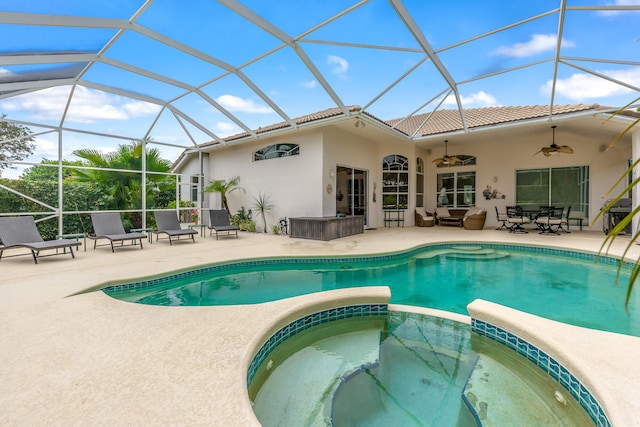 back of house with ceiling fan, a lanai, a swimming pool with hot tub, and a patio area