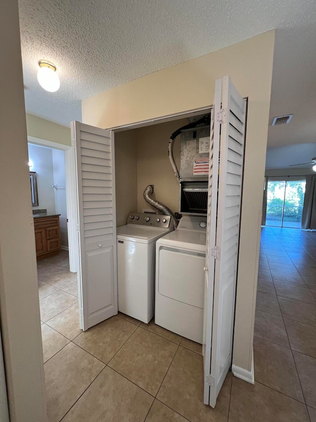 washroom featuring a textured ceiling, washer and dryer, and light tile patterned floors