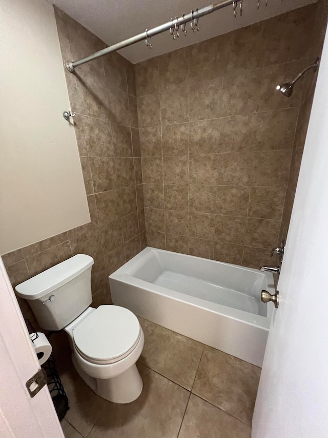 bathroom featuring tile patterned flooring, toilet, tile walls, and tiled shower / bath combo