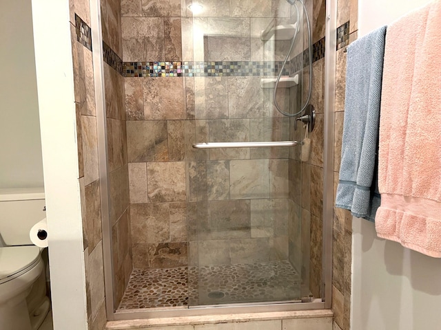 bathroom featuring toilet and a shower with shower door