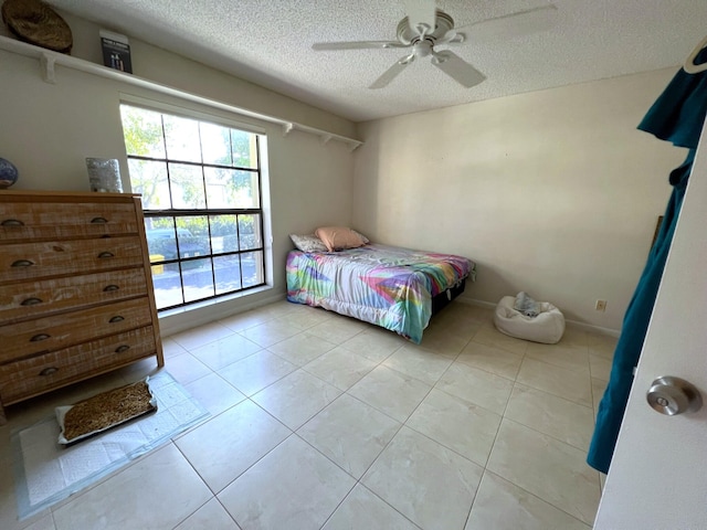 bedroom with a textured ceiling, light tile patterned floors, and ceiling fan