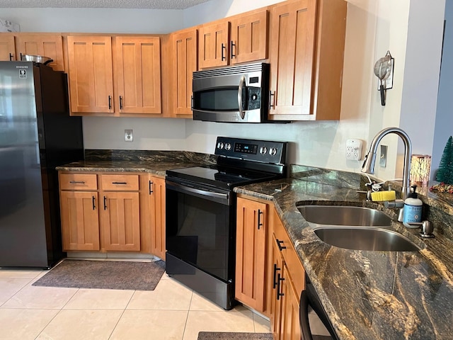 kitchen with sink, light tile patterned floors, black electric range oven, fridge, and dark stone countertops