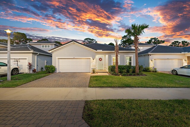 200 SW Pomeroy St, Stuart, FL 34997 - view of front facade featuring a garage, decorative driveway, stucco siding, a lawn, and a tile roof