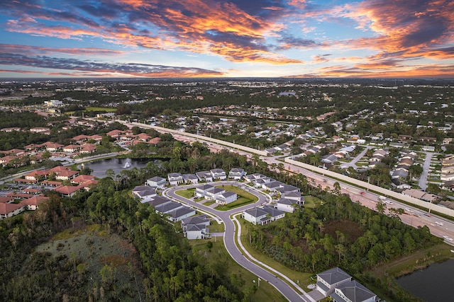 aerial view at dusk featuring a water view