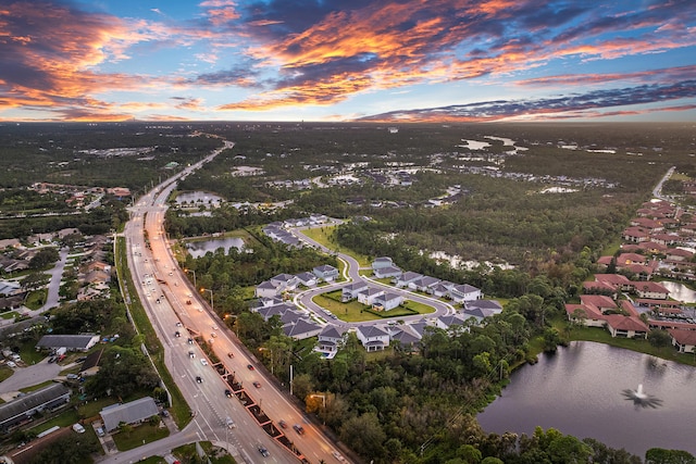 aerial view at dusk featuring a water view