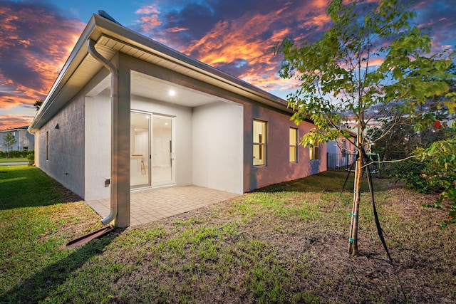 back house at dusk with a yard and a patio area