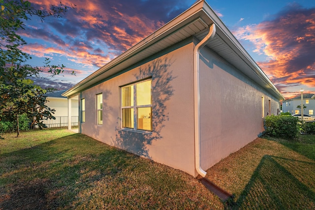 property exterior at dusk with a lawn