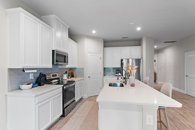 kitchen with light hardwood / wood-style floors, sink, a center island with sink, and stainless steel appliances